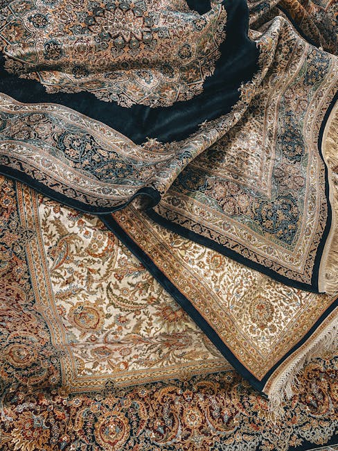 Close-up of a collection of intricately patterned Persian-style rugs with detailed floral and geometric designs in shades of beige, gold, blue, and rust. The rugs are layered, with some edges folded over, revealing both the top and underside, in a well-lit room that accentuates their rich textures. The surfaces appear clean, with no visible stains or dust, suggesting professional deep cleaning and maintenance by Knightsbridge Carpet Cleaners, as featured on the Eaton Square rug cleaning and stain removal page. The image emphasizes the quality and condition of the rugs, highlighting the importance of thorough surface cleaning and preservation in a residential or commercial setting.